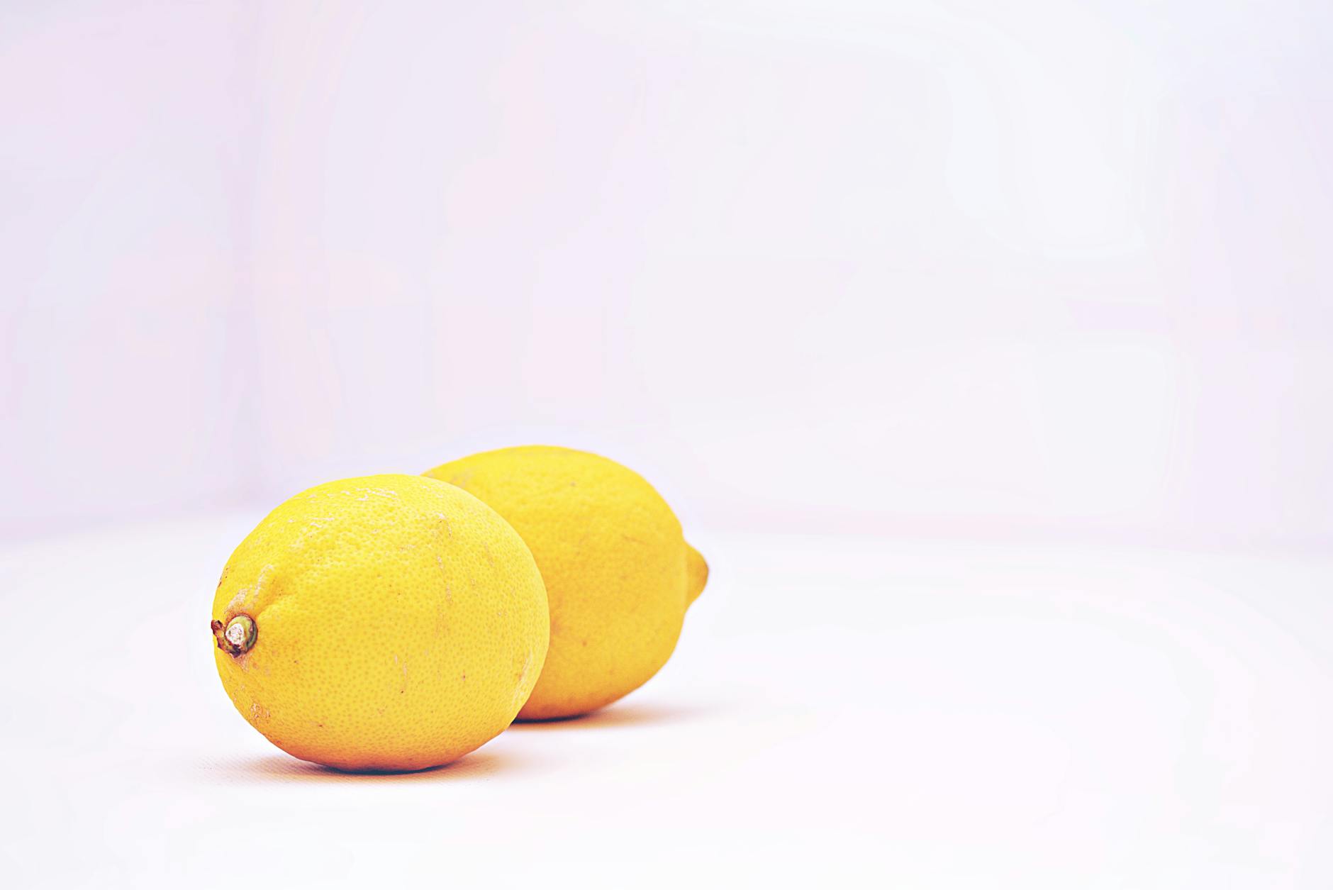 Two vibrant lemons on a white minimalist background representing fresh sensitivity and renewal