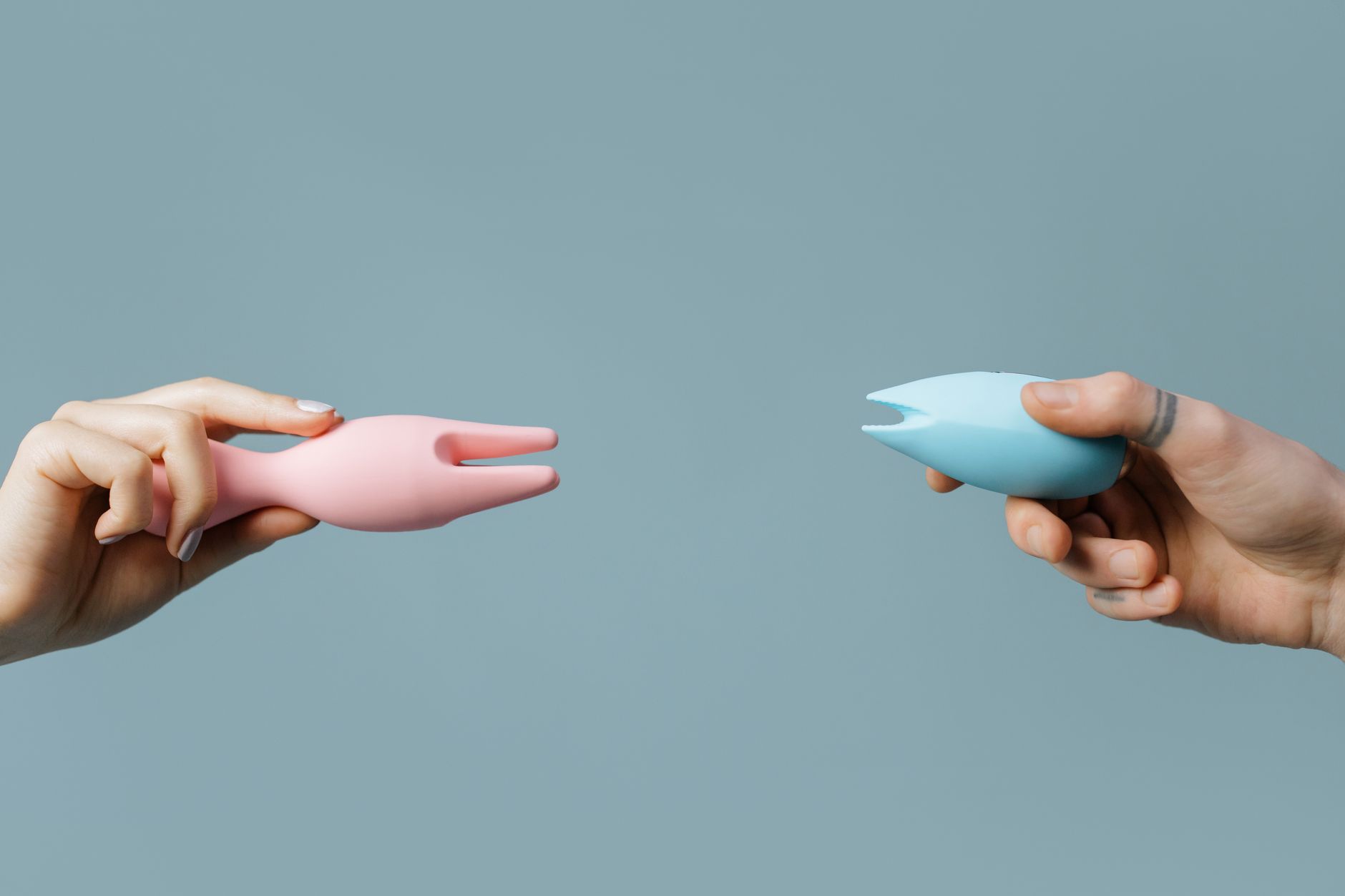 A young couple standing together indoors, holding a blue vibrator, symbolizing modern intimacy and reconnection.
